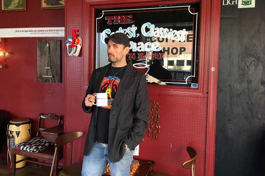 Logan County cafe owner Michael Cline stands with a coffee cup in his hand.