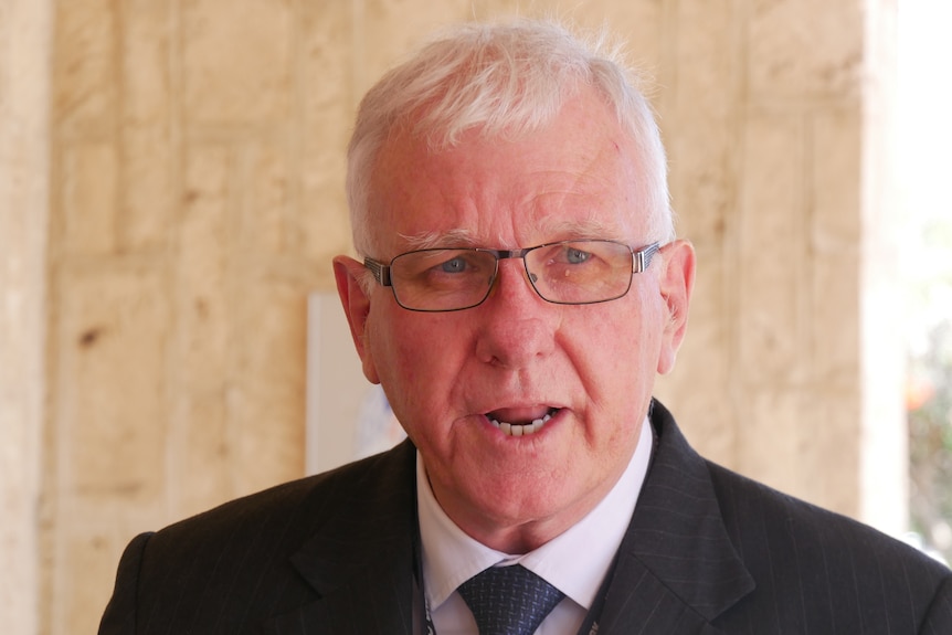 Headshot of a man wearing a suit and glasses.