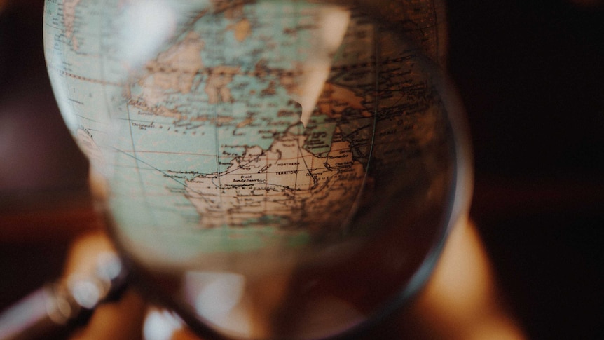 A round globe of the world in sepia tone, the camera focuses on Australia