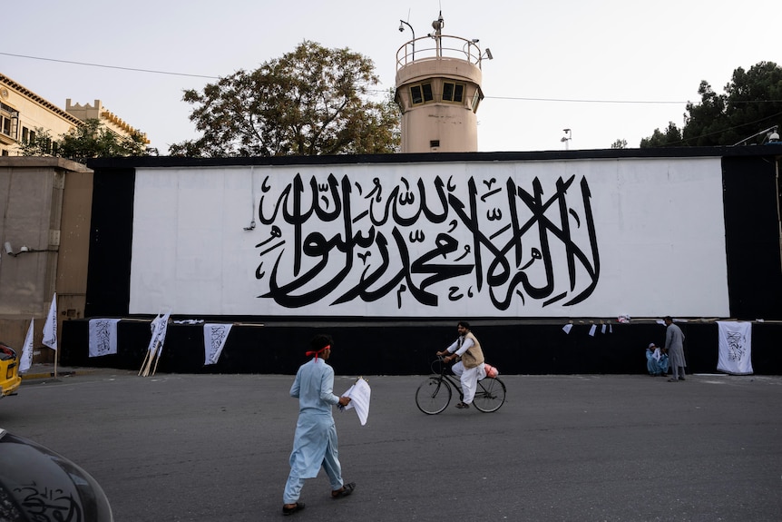 A white sign with black lettering is fixed to a wall