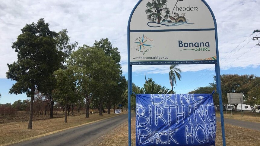 A sign at the entrance of the Town of Theodore has a banner attached to it that reads "Bring birthing back home"