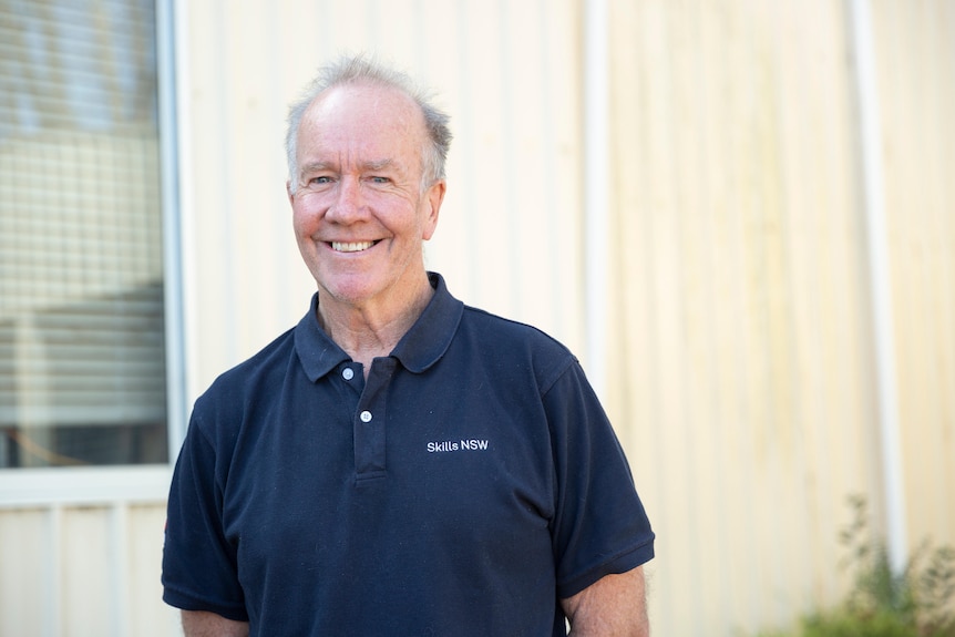 A man smiling and looking at the camera outside