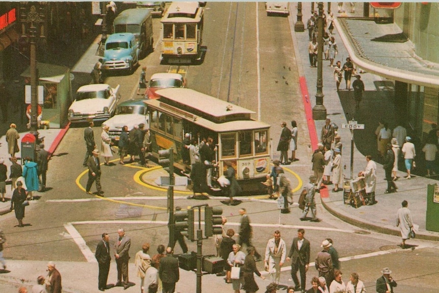 Cars, pedestrians and a trolley meet at an intersection in an aged postcard