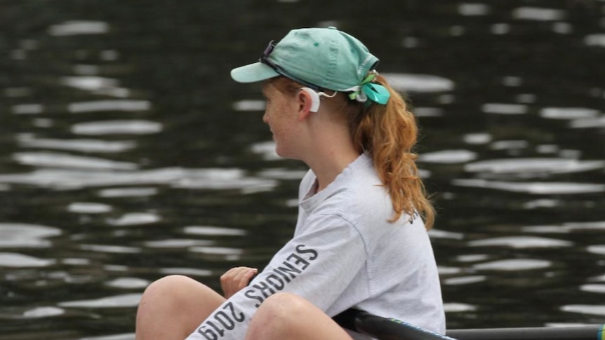 A young woman in a canoe/kayak in the water with a hearing aid 