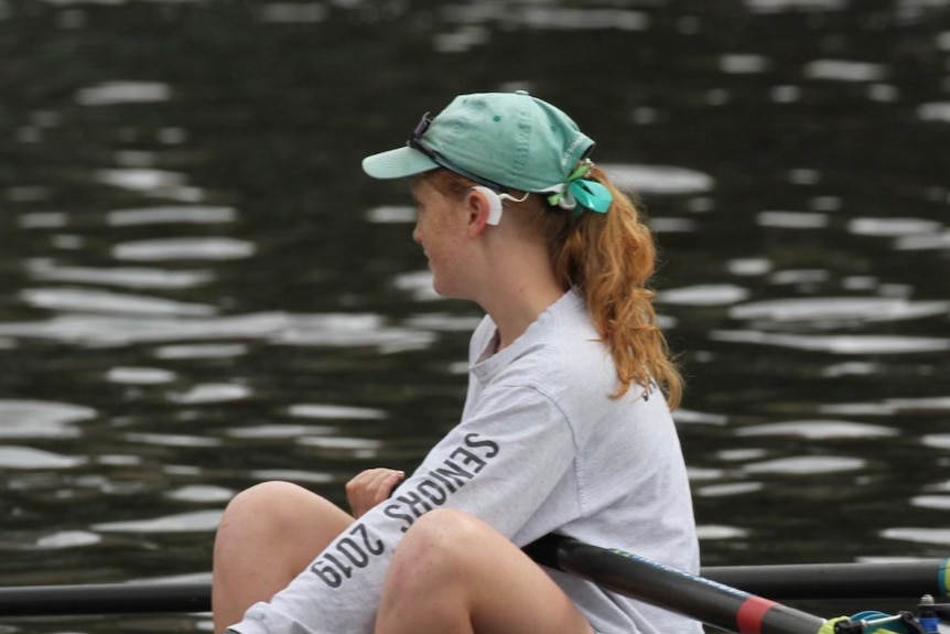 A young woman in a canoe/kayak in the water with a hearing aid 