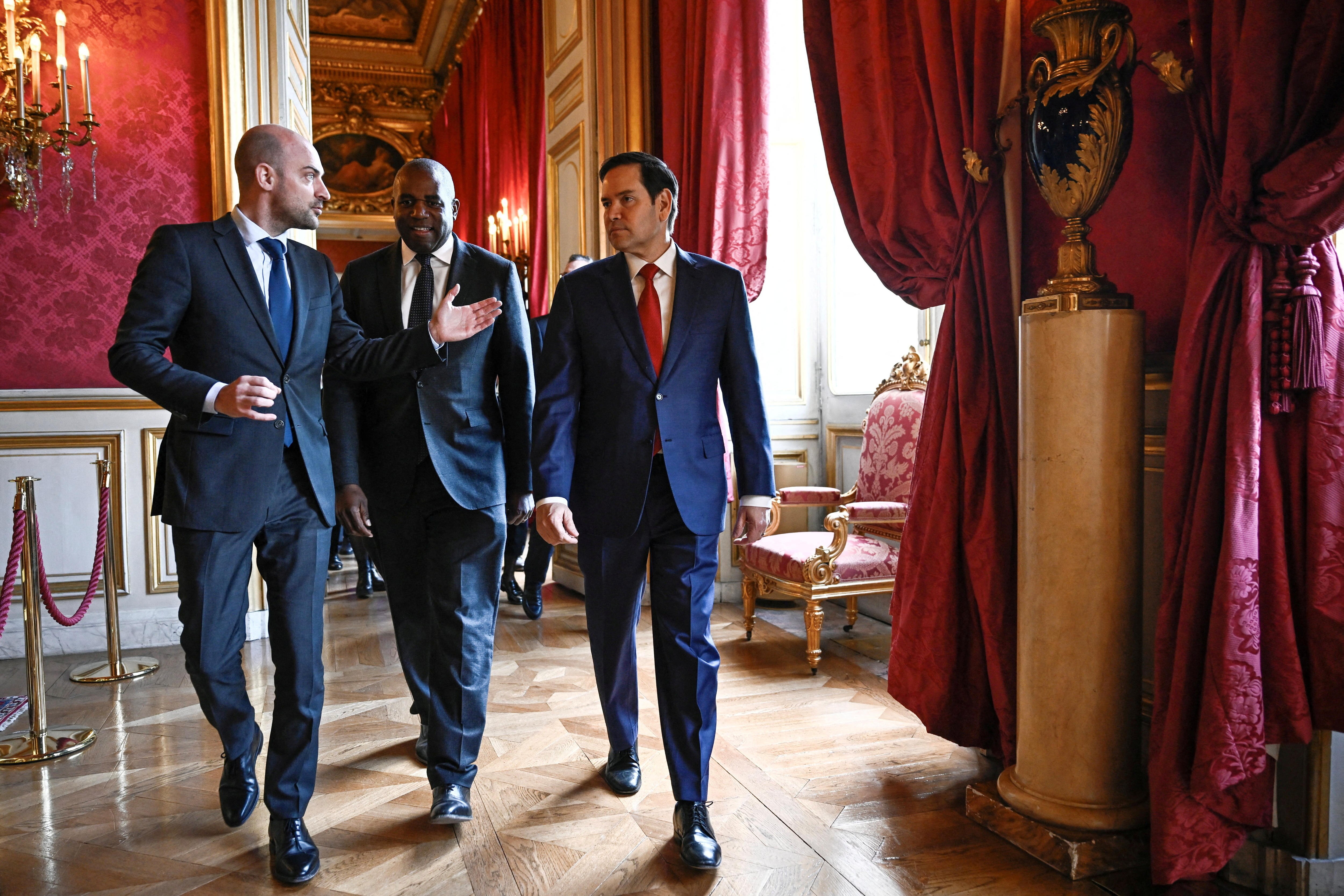 Three men walk through a hallway