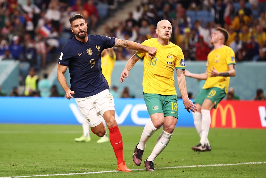 France's Olivier Giroud runs away from Socceroos' Aaron Mooy after a goal in their Qatar World Cup game.