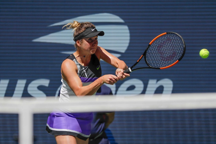 A tennis player hits a two-handed backhand return at the US Open.