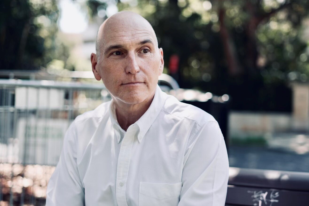 a man in a white shirt sitting contemplating