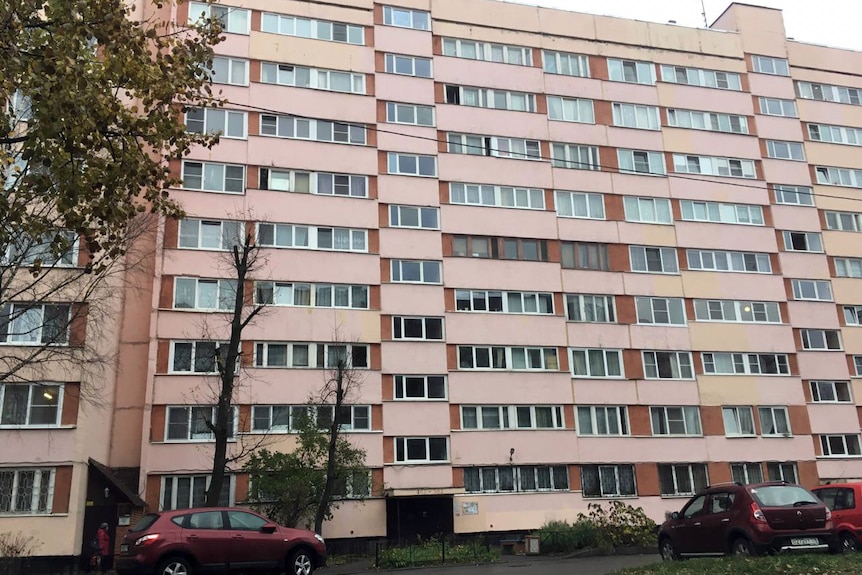 The outside of a large, somewhat run-down nine-storey apartment block. Photo taken from the road.