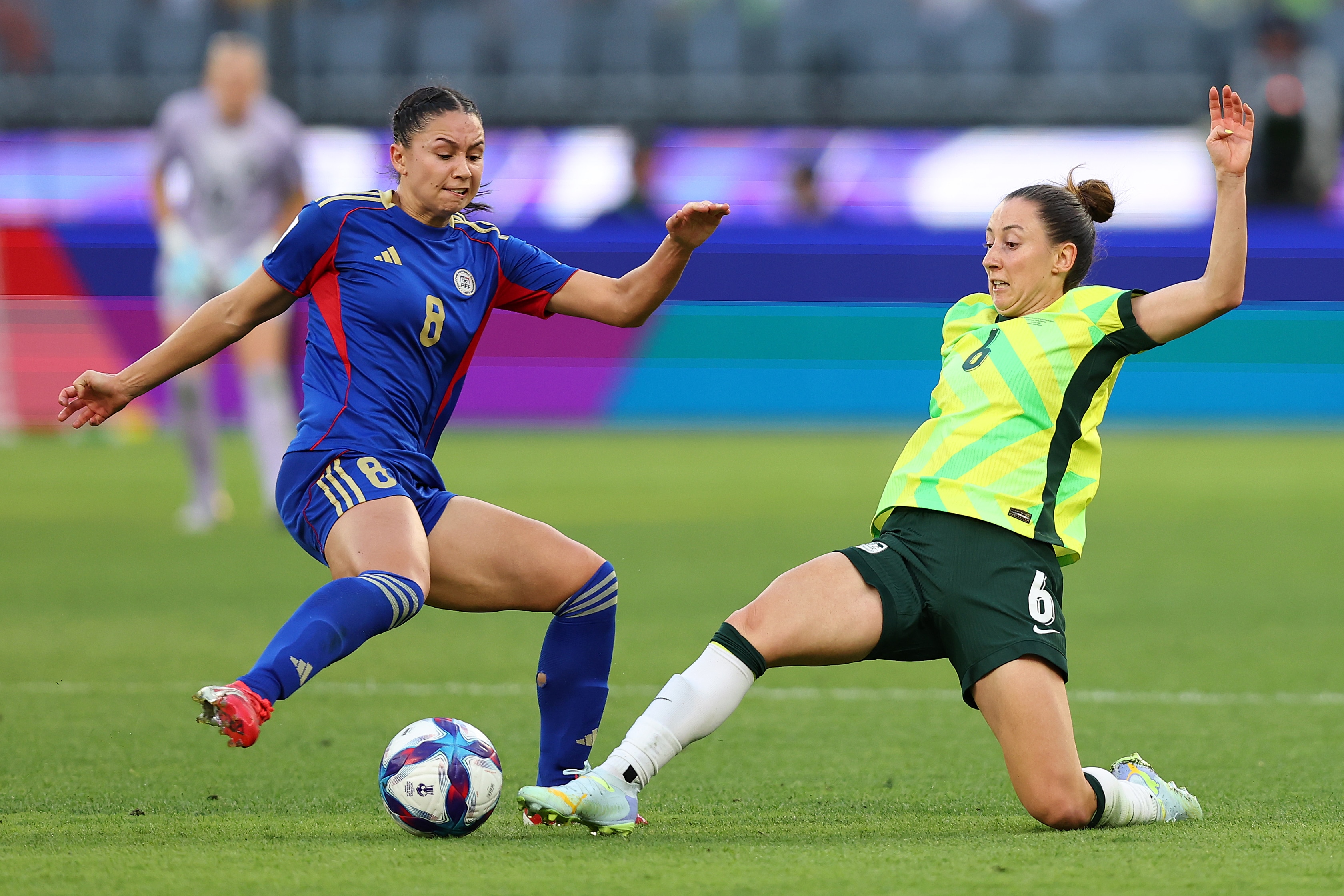 A jogadora do Matildas, Clare Wheeler, ataca a bola, enquanto um jogador das Filipinas se aproxima