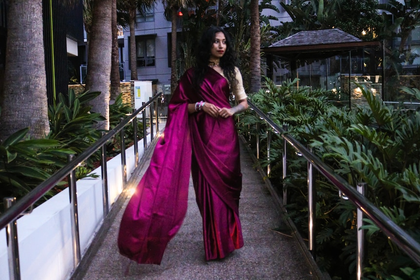 A woman wearing a Saree standing in the middle of an aisle