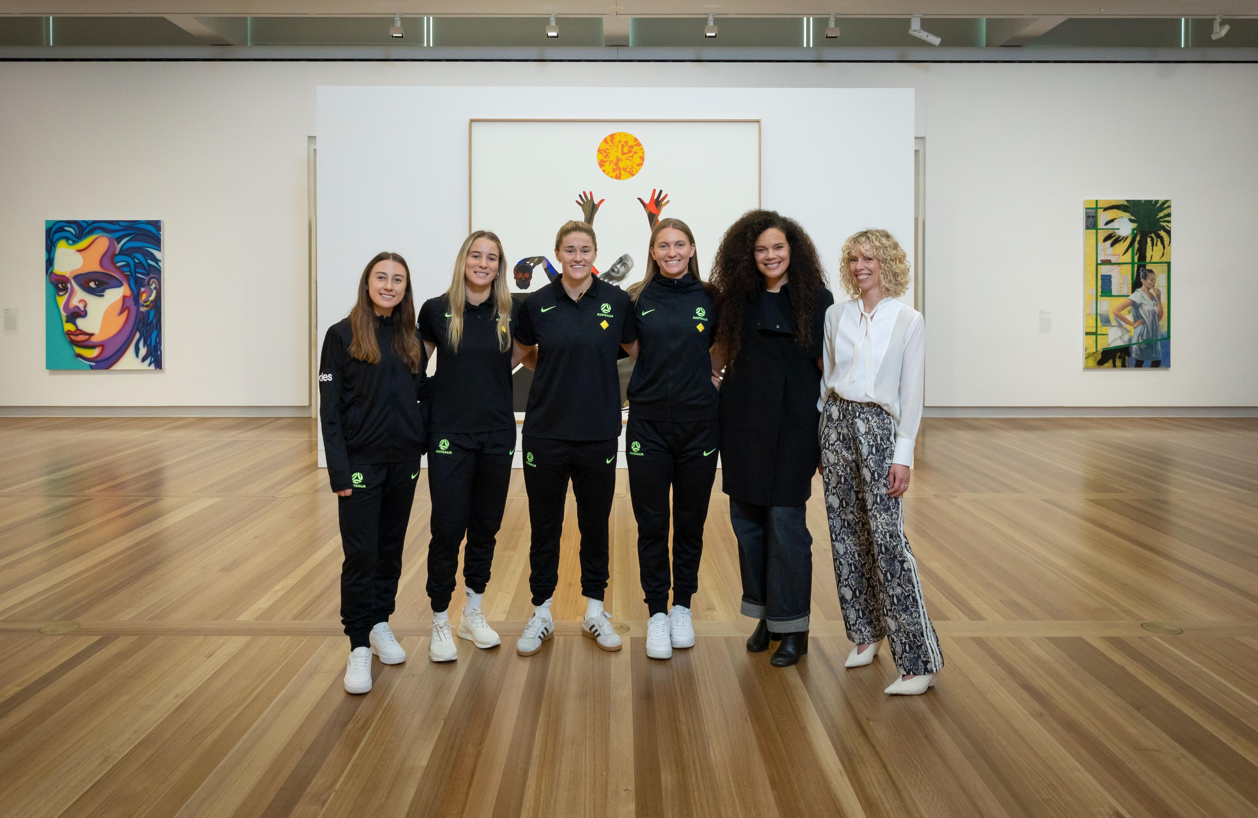 Matildas players pose for a photo with artist Angela Tiatia and National Portrait Gallery director Bree Pickering.