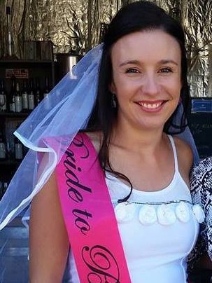 A woman in a white dress with a pink sash that reads 'bride to be'.