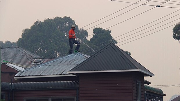 Roof is watered in Geeveston as bushfire burns nearby, Australia Day, 2019.