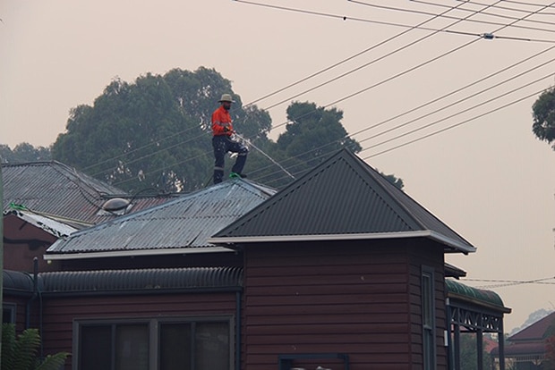Roof is watered in Geeveston as bushfire burns nearby, Australia Day, 2019.