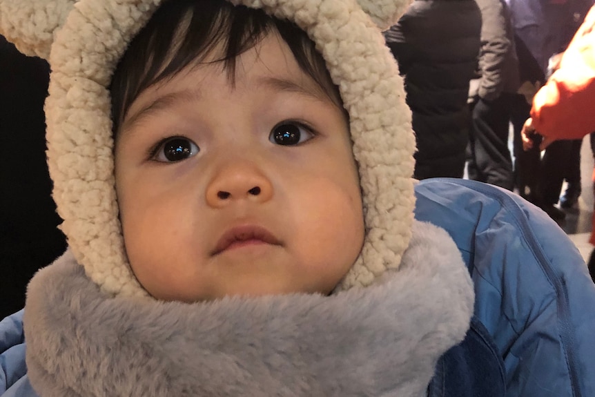 A boy wears a bear hoodie on the streets.