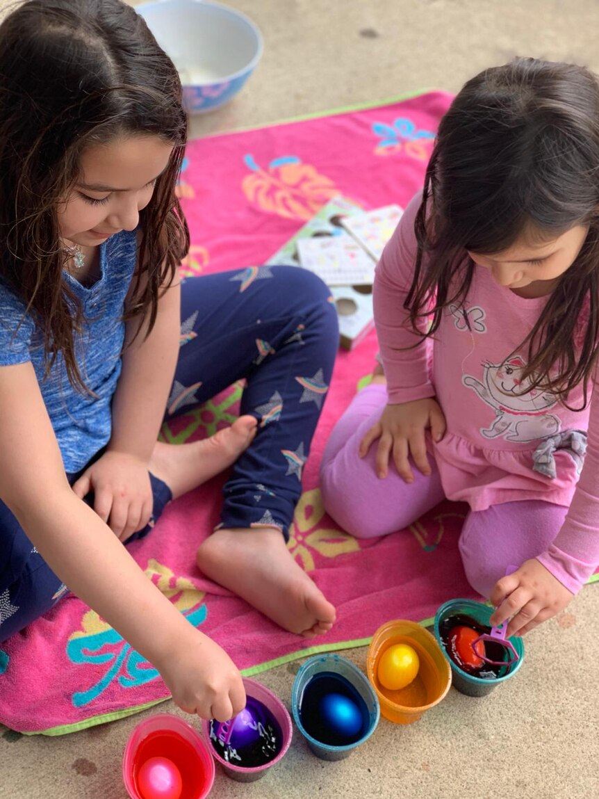 Two children sit on a rug.