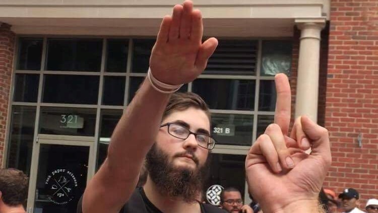 A man raises his hand in a Nazi salute as another person gives him the finger.
