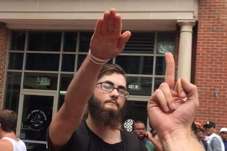 A man raises his hand in a Nazi salute as another person gives him the finger.