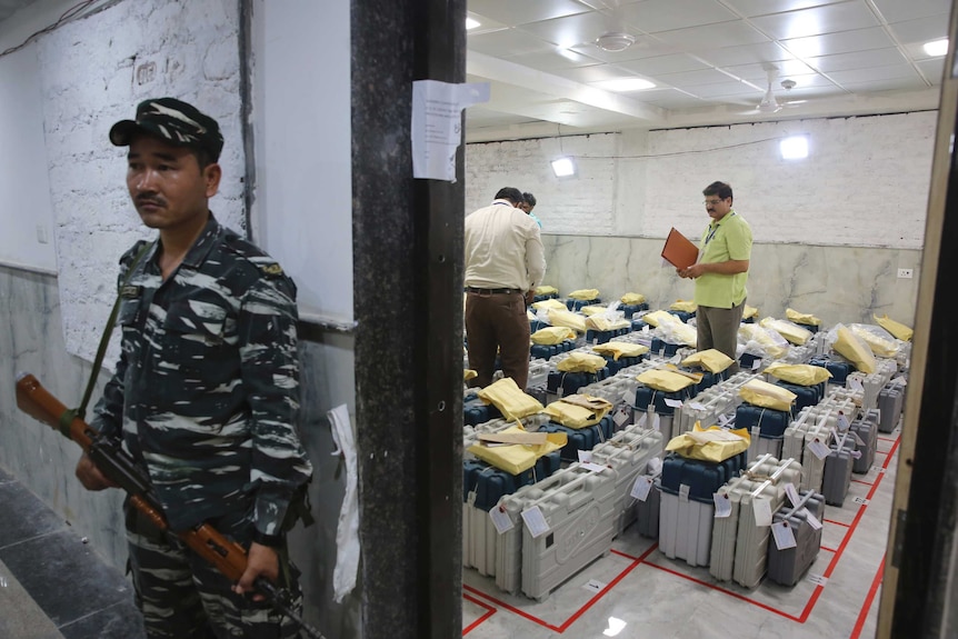 An Indian paramilitary soldier stands guard outside a room where voting machines.