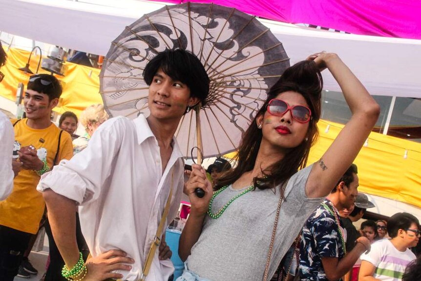 A woman in red sunglasses poses with a friend under a parasol