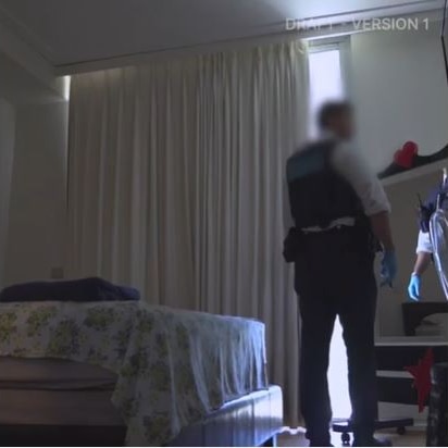 A policeman looks through a bedroom during a search of a property.