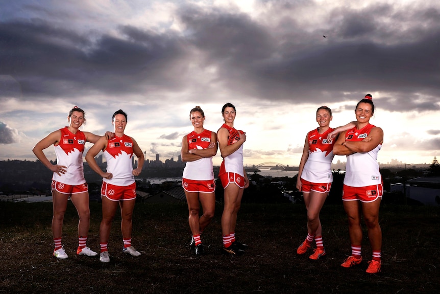 Six women stand on a hill overlooking Sydney on a stormy day