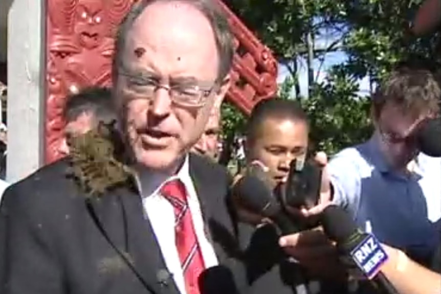 A politician wearing a suit had a chunk of mud hit him in the face 