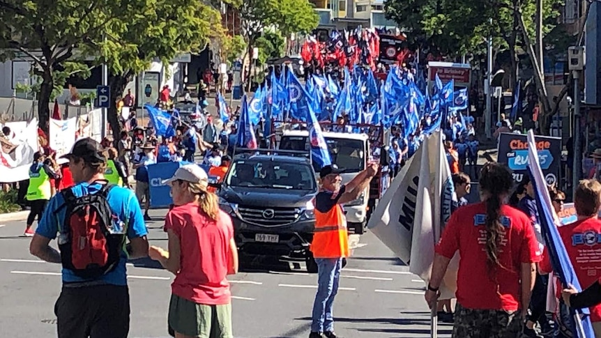 Union members march with banners through Brisbane's CBD on Labour Day.