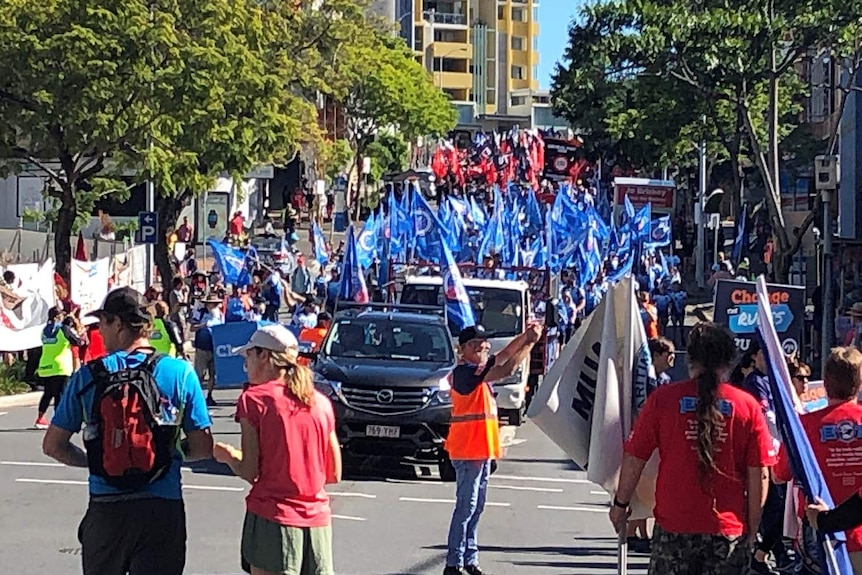 Union members march with banners through Brisbane's CBD on Labour Day.
