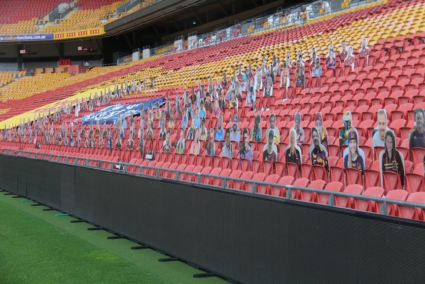 Cardboard cut outs of fans placed on empty seats in an empty stadium.