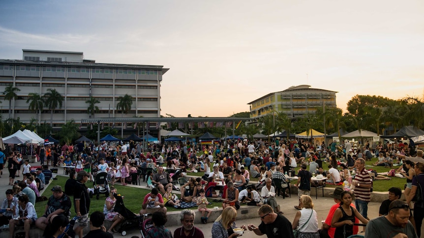 Hundreds gathered at a city square at sunset.