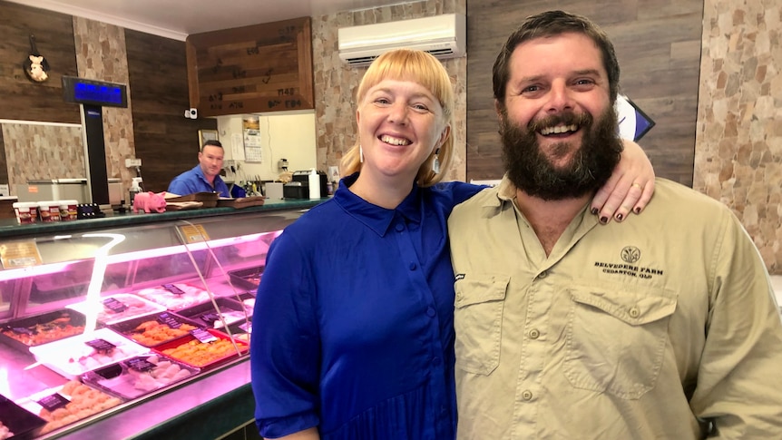 A smiling woman and man in a butcher's shop.