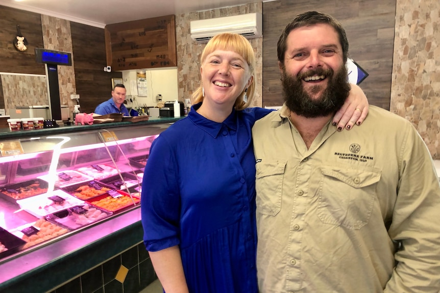 A smiling woman and man in a butcher's shop.