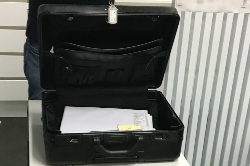 Large briefcase sits open on a filing cabinet with a pile of secret government documents sitting inside.
