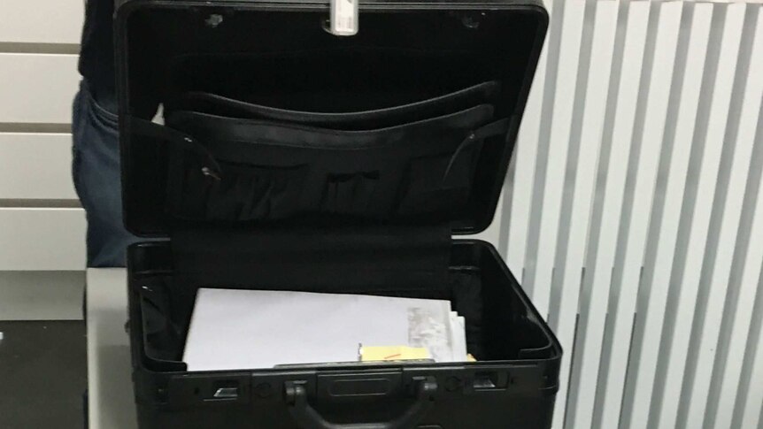 Large briefcase sits open on a filing cabinet with a pile of secret government documents sitting inside.