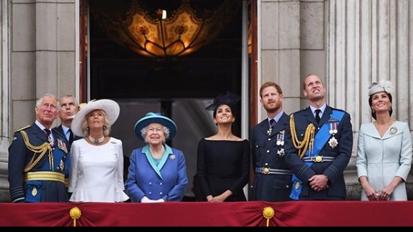 The royal family stands on a balcony.