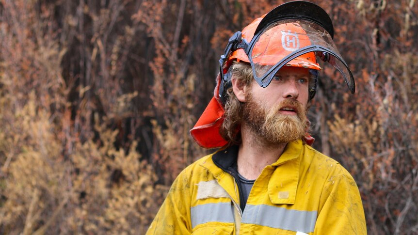A man dressed in bright yellow protective gear in the Tasmanian wilderness during the 2016 bushfires.