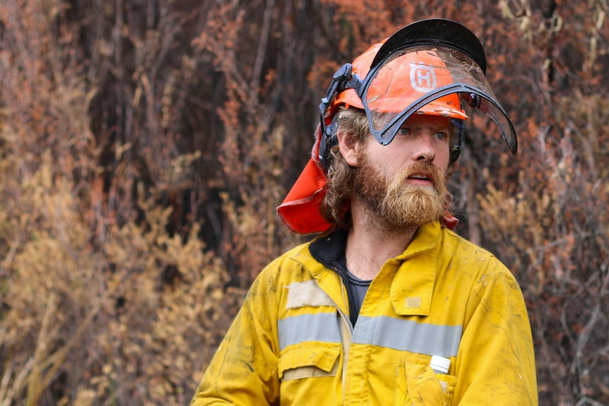 A man dressed in bright yellow protective gear in the Tasmanian wilderness during the 2016 bushfires.