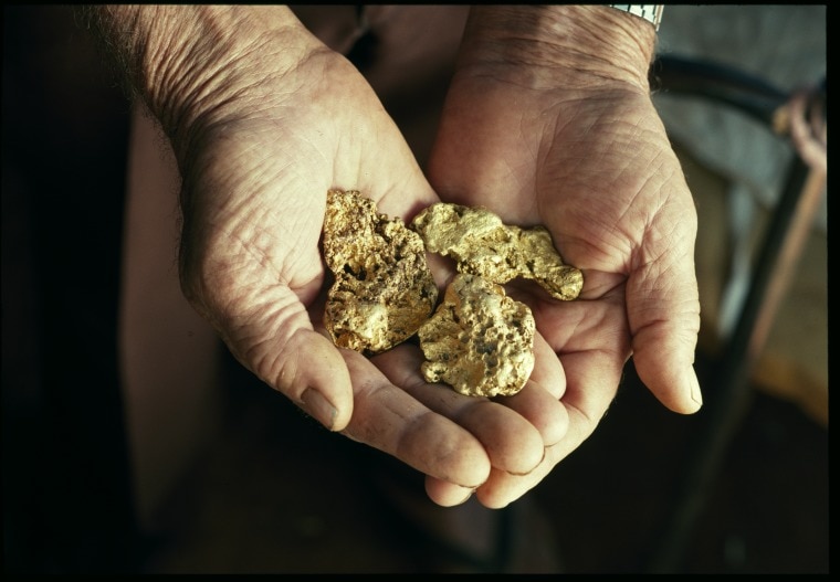 nuggets of gold in the palms of two hands.