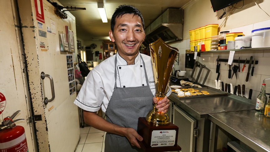 Chan Khun holding his big golden trophy.