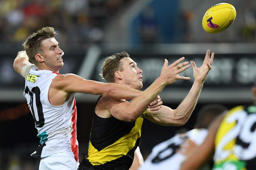 A Richmond AFL player attempts to take a mark in front of a St Kilda opponent.