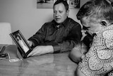 Black and white picture of Mark and Adam James look at a photo of their mother, Maria