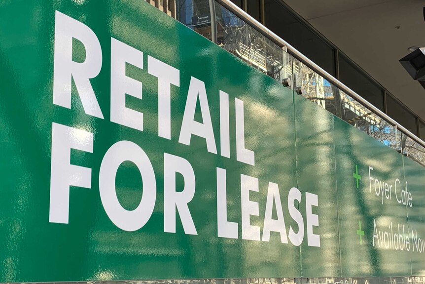 A large green sign with white lettering saying retail for lease.
