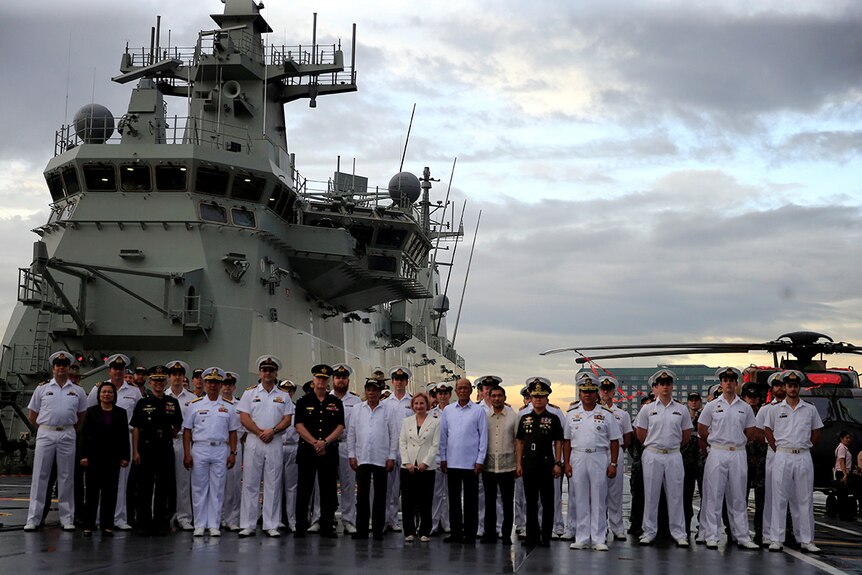 Rodrigo Duterte poses in the centre of dozens of Australian Navy officials in front of HMAS Adelaide.