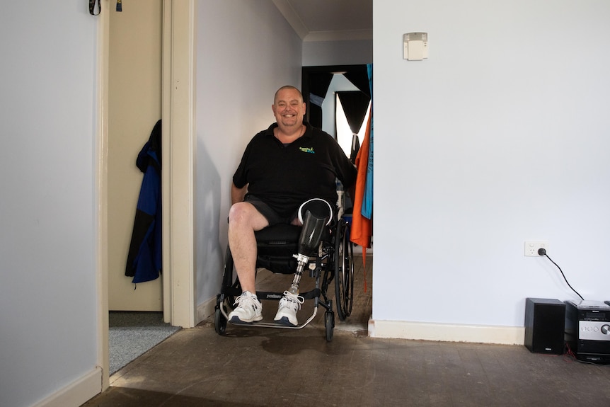  Andrew Fairbairn sitting in his wheelchair in his home.