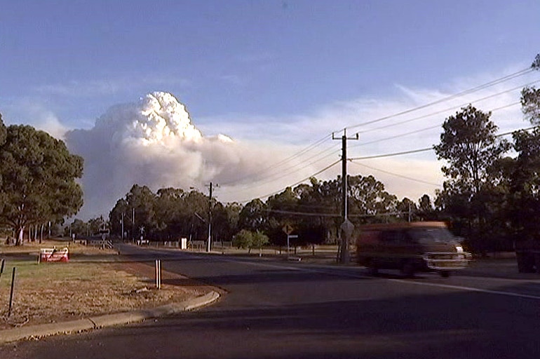 A big smoke cloud can be seen from the streets of a country town.