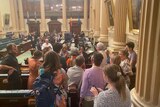 A group of people embrace in the State Parliament building.