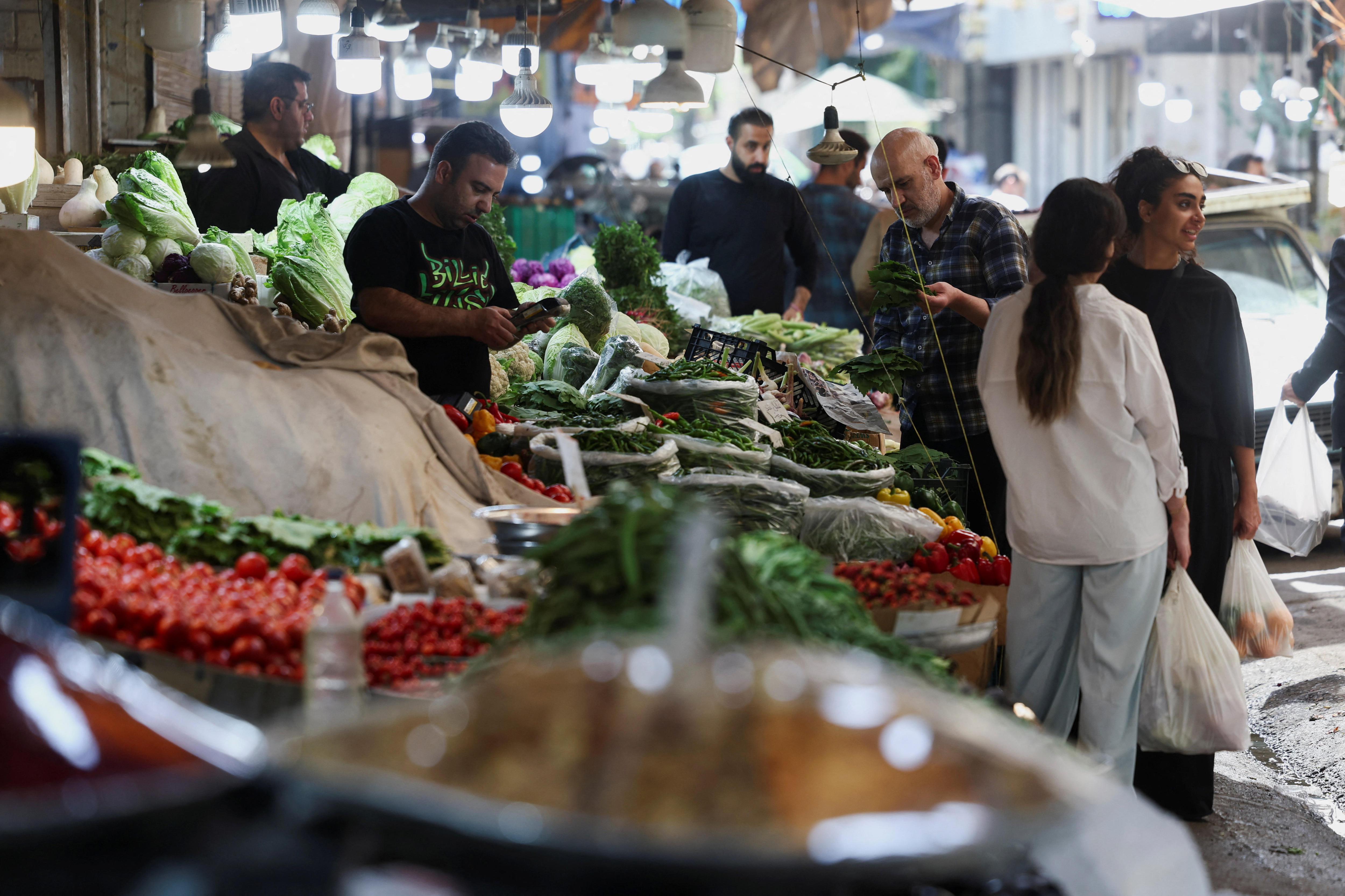 Iranian local fruits and vegetables market and people shopping at stalls.